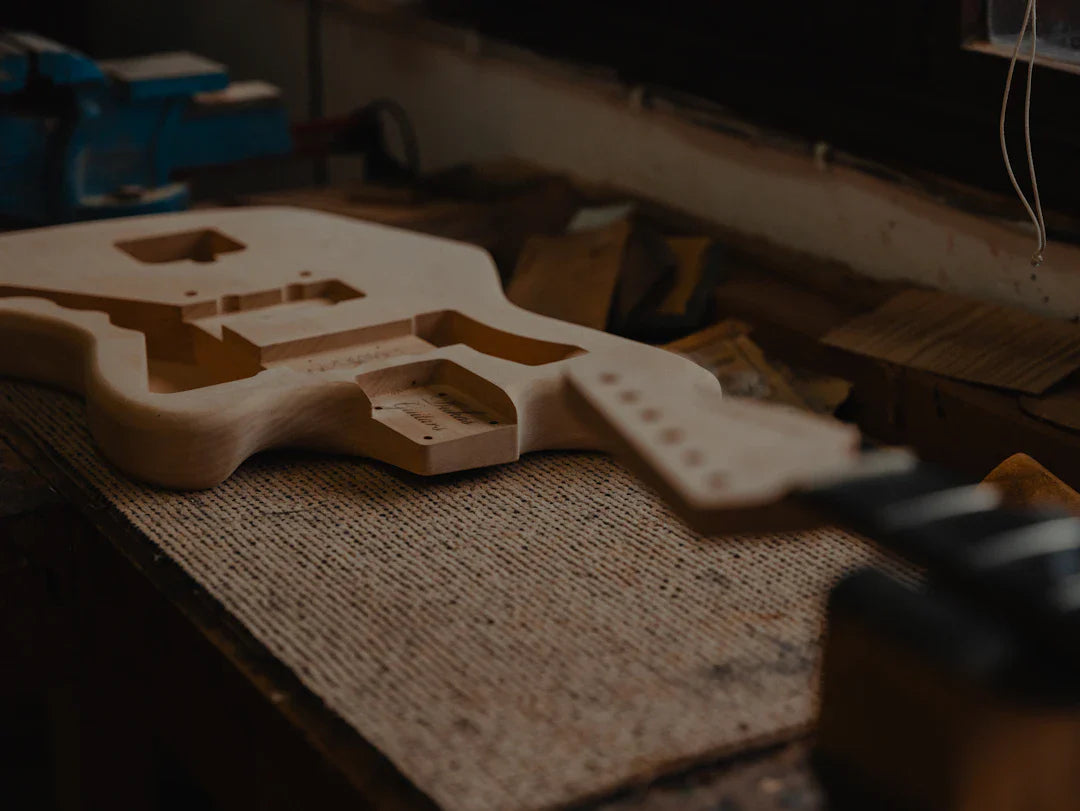 Unfinished electric guitar body and neck on workshop bench, custom American guitar build