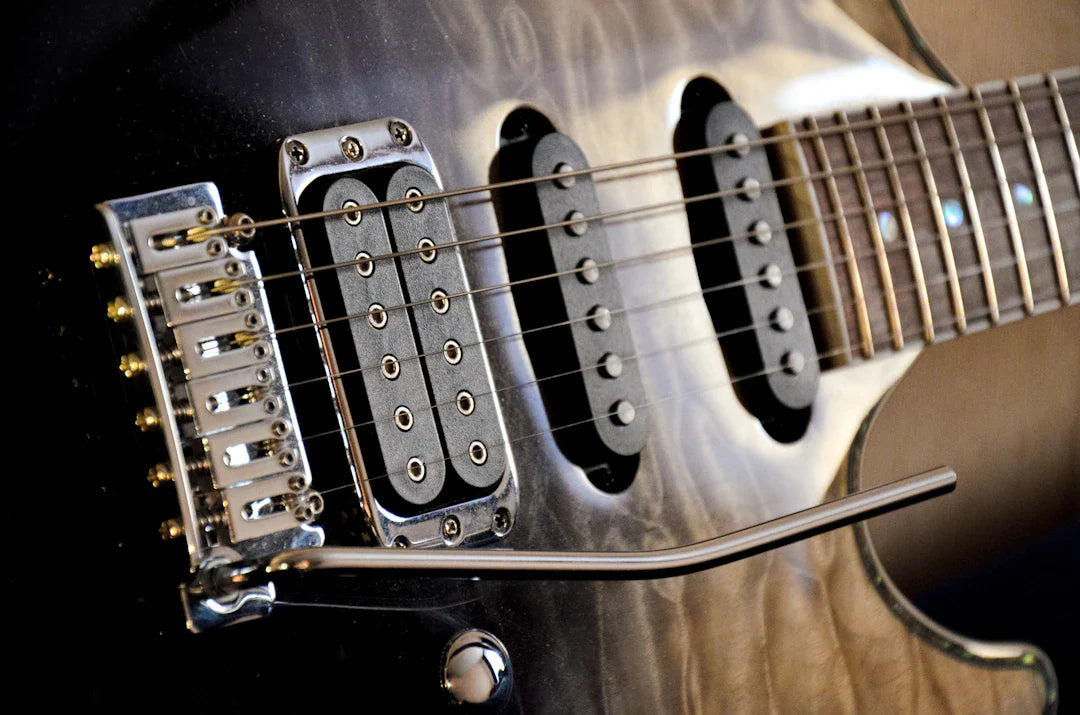 Close-up of a high-end electric guitar with quilted maple top, humbucker pickup, and tremolo bridge