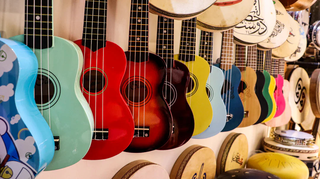 Colorful electric guitars and ukuleles hanging on a wall in a music store display.