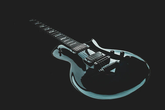 Glossy black electric guitar with dual humbucker pickups on a dark background