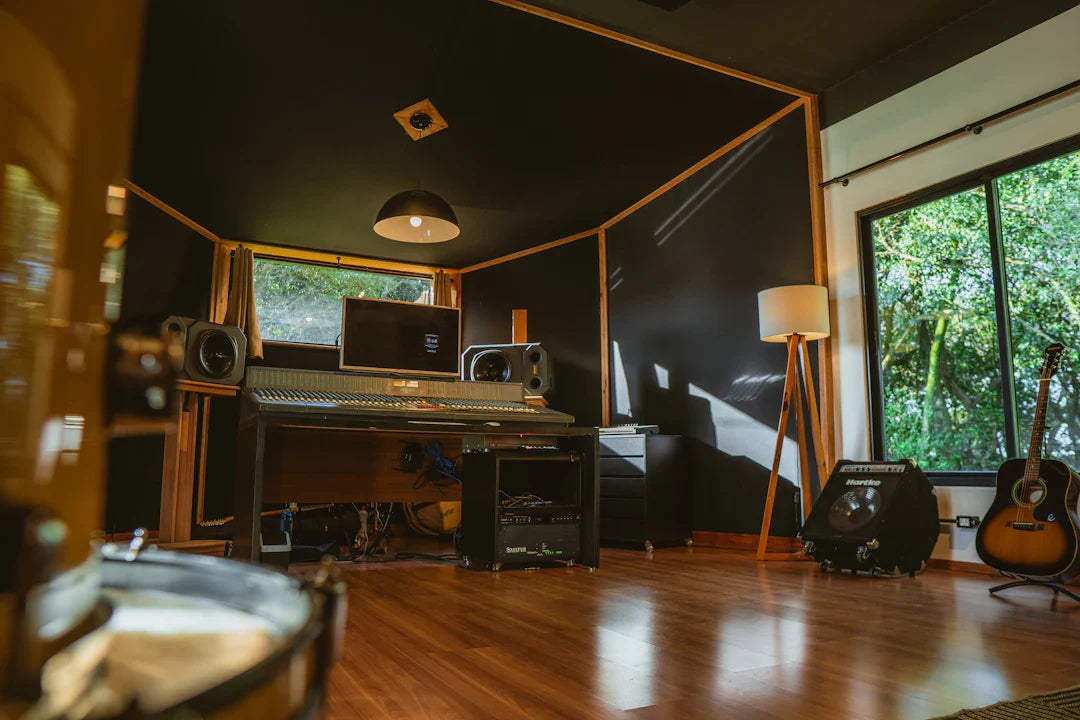 Modern recording studio with acoustic guitar, amplifiers, mixing desk, and wood floors